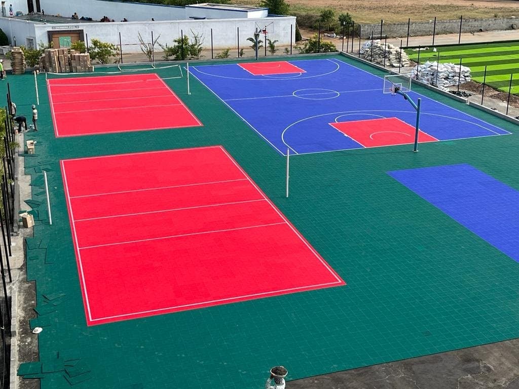 Aerial view of red volleyball and blue basketball tile courts at PA International School, Pollachi, built by Fitoverse
