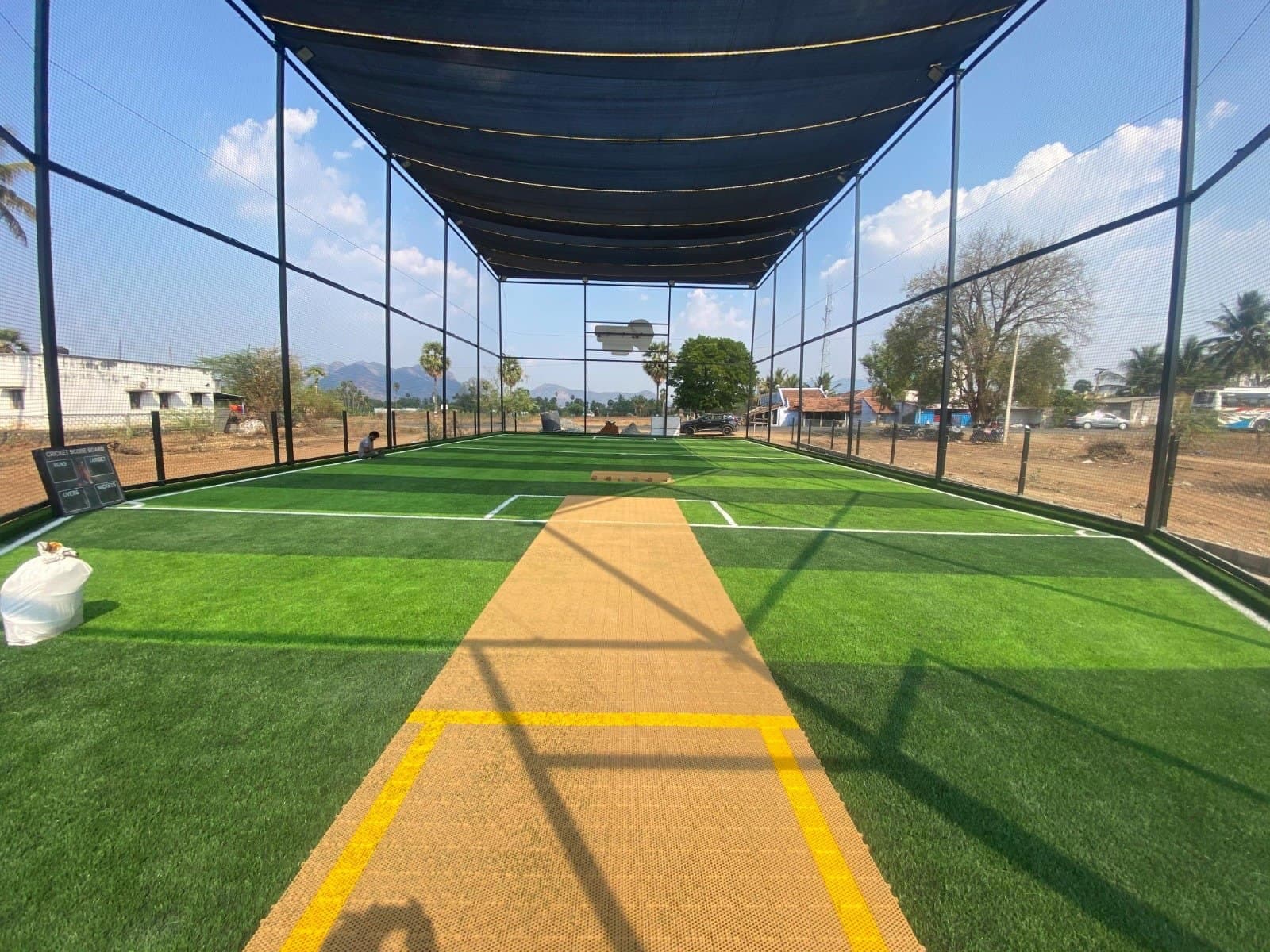 Netted cricket turf with a tan pitch strip and shade-net roof at Turf RNA, Salem, built by Fitoverse